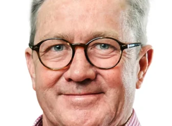 A professional headshot of Ben Barlow, AWN Non-Executive Director, smiling. He is a man with grey hair and round, dark-rimmed glasses, wearing a red and white checkered collared shirt, against a plain white background.