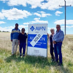 Acerage land in Charam Victoria. Green grass and blue sky while family pose standing next to the sold sign of the recent purchase.