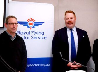 Following the AWN Charity Auction for the Royal Flying Doctor Service in Melbourne. Left to right is Stephen Bryce PJ Morris Wool Buyer, Jeff Denny AWN Wool Technical Manager/Senior Auctioneer and Caroline Lee RFDS Partnership and Engagement Specialist. They are all standing next to a Royal Flying Doctor Service banner after the charity wool auction.