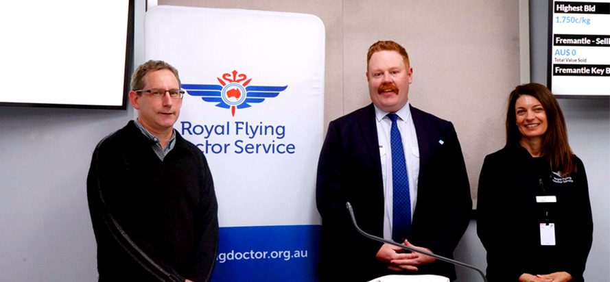 Following the AWN Charity Auction for the Royal Flying Doctor Service in Melbourne. Left to right is Stephen Bryce PJ Morris Wool Buyer, Jeff Denny AWN Wool Technical Manager/Senior Auctioneer and Caroline Lee RFDS Partnership and Engagement Specialist. They are all standing next to a Royal Flying Doctor Service banner after the charity wool auction.