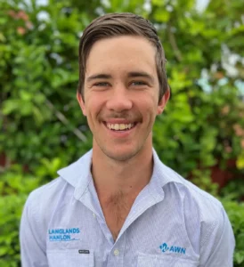  Query successful A headshot of Clint Hooper, a Livestock Specialist for AWN Parkes and Langlands Hanlon. He is a young man with a moustache, smiling and wearing a blue and white striped work shirt with the AWN and Langlands Hanlon logos on it. The background is a green hedge.
