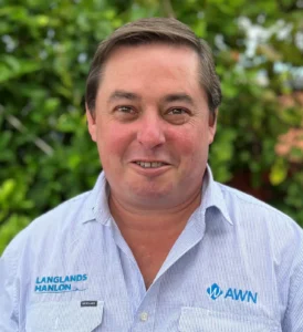 Query successful A headshot of Greg Miller, a Rural Real Estate Representative for AWN Parkes and Langlands Hanlon. He is a man with brown hair, smiling and wearing a blue and white striped work shirt with the AWN and Langlands Hanlon logos on it. The background is a green hedge.