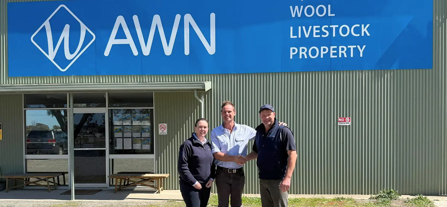 An alt text for the provided text is: **Image of Lauren Smith, Michael Phelan, and Wayne Driscoll shaking hands in front of the AWN Horsham branch. Michael Phelan is the new Wimmera Branch Manager, taking over from Wayne Driscoll.**